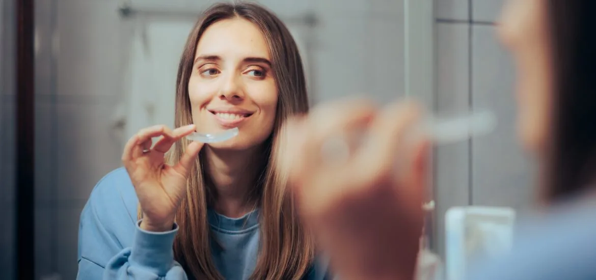 Woman Taking off Her Clear Retainer in the Bathroom Mirror, teeth grinding protection at night