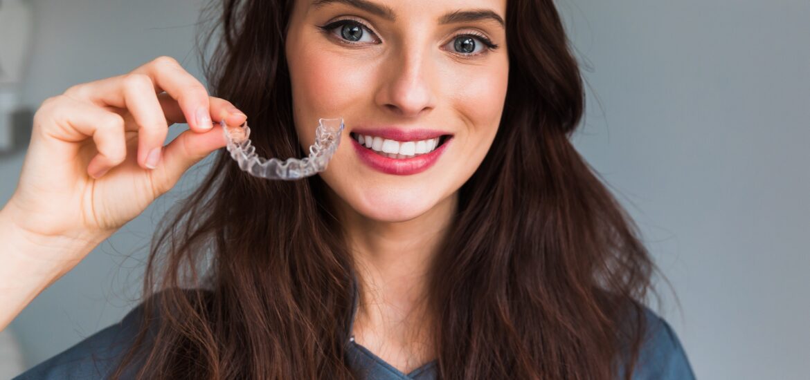 Young beautiful woman holding dental aligner