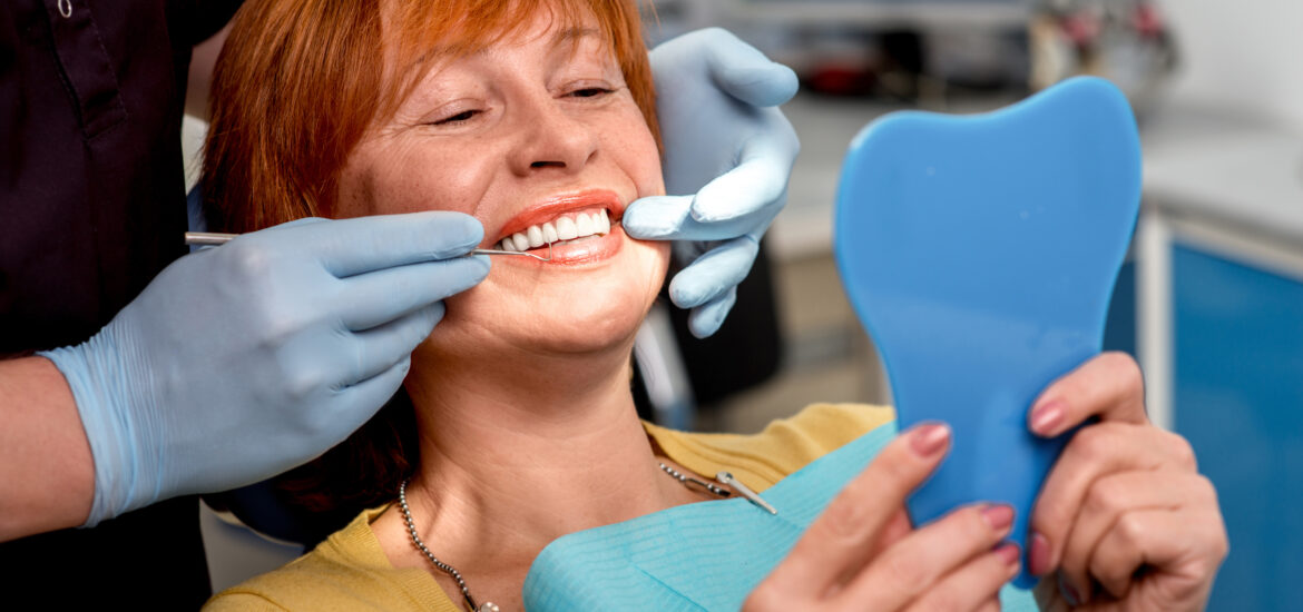 doctor in blue gloves showing a female patient her new dental bridge
