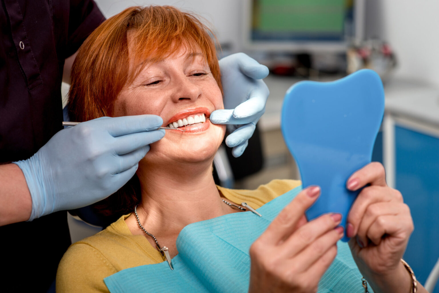 doctor in blue gloves showing a female patient her new dental bridge