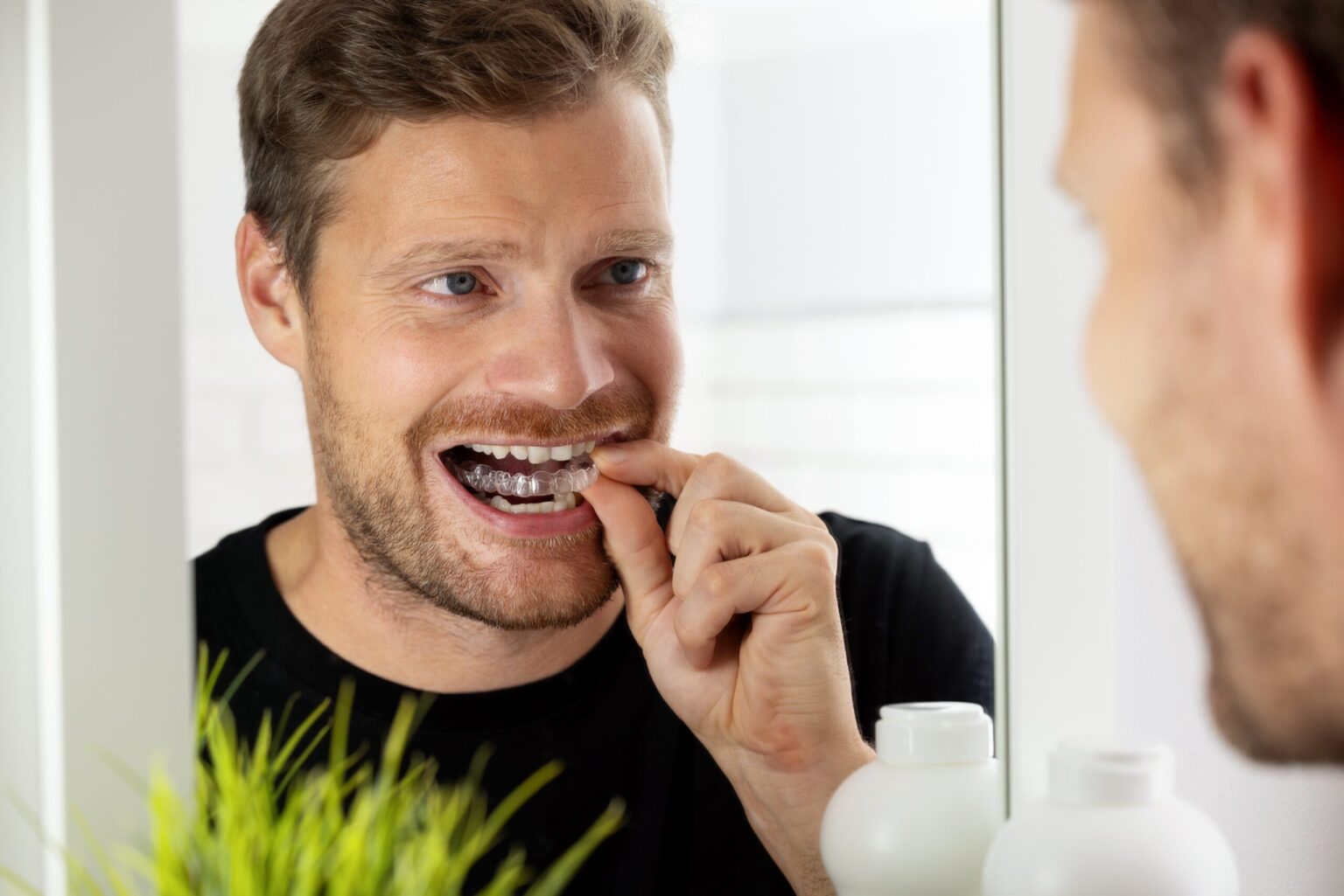 middle aged man looking in the mirror, inserting his Invisalign