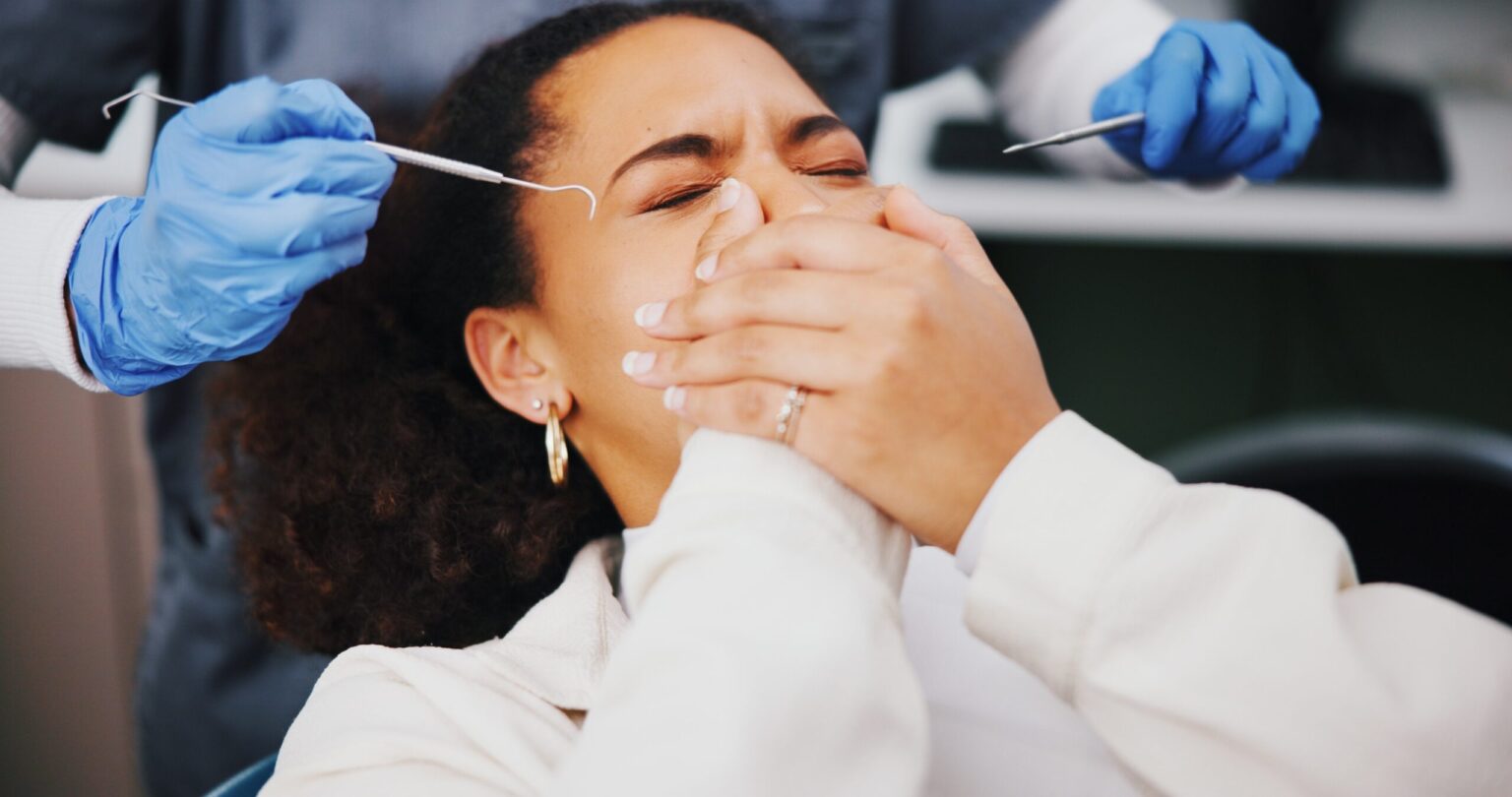 female dental patient covering her mouth in fear