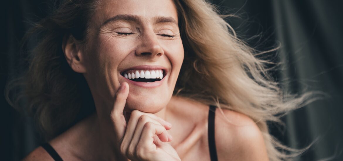 blonder woman smiling with her eyes closed, showing perfect white smile