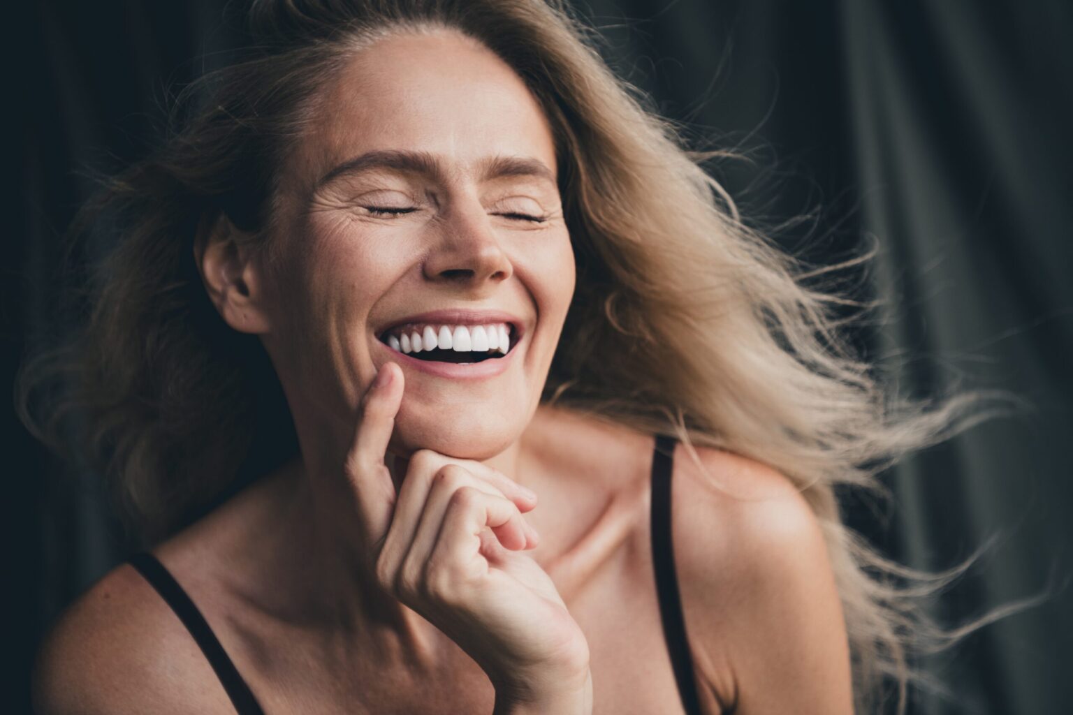 blonder woman smiling with her eyes closed, showing perfect white smile