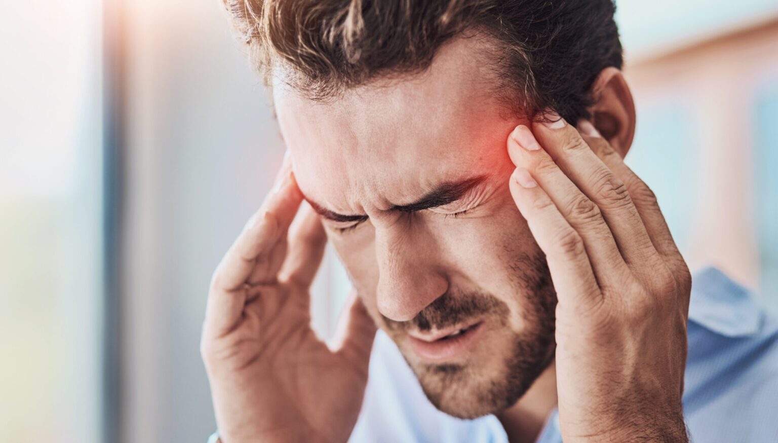 man with a headache massaging his temples