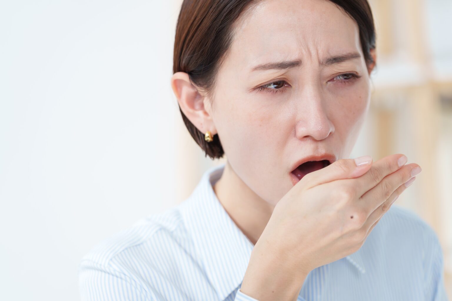 A woman worried about having bad breath, blowing on her hand, chronic dry mouth syndrome