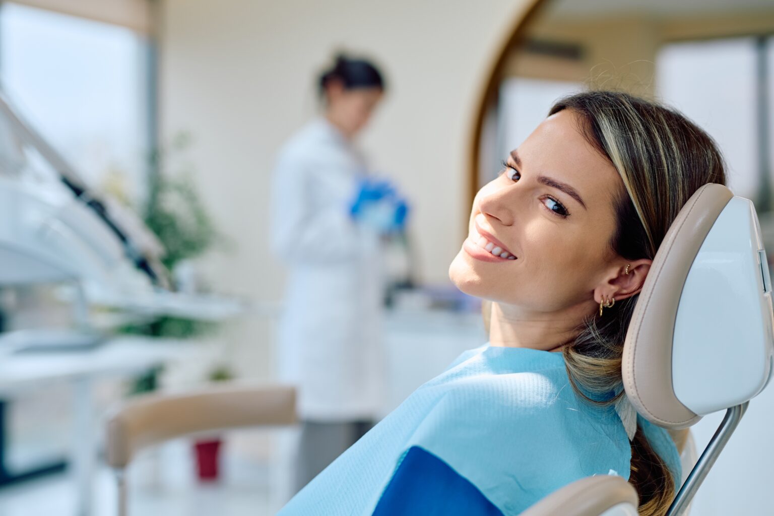 young woman smiling in a dental chair, newly bonded tooth
